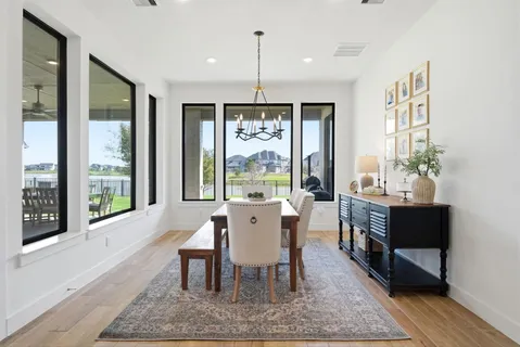 a dining room with wooden floor a chandelier a wooden table and chairs
