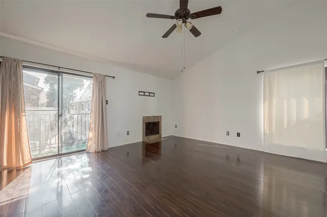 an empty room with wooden floor fan and windows