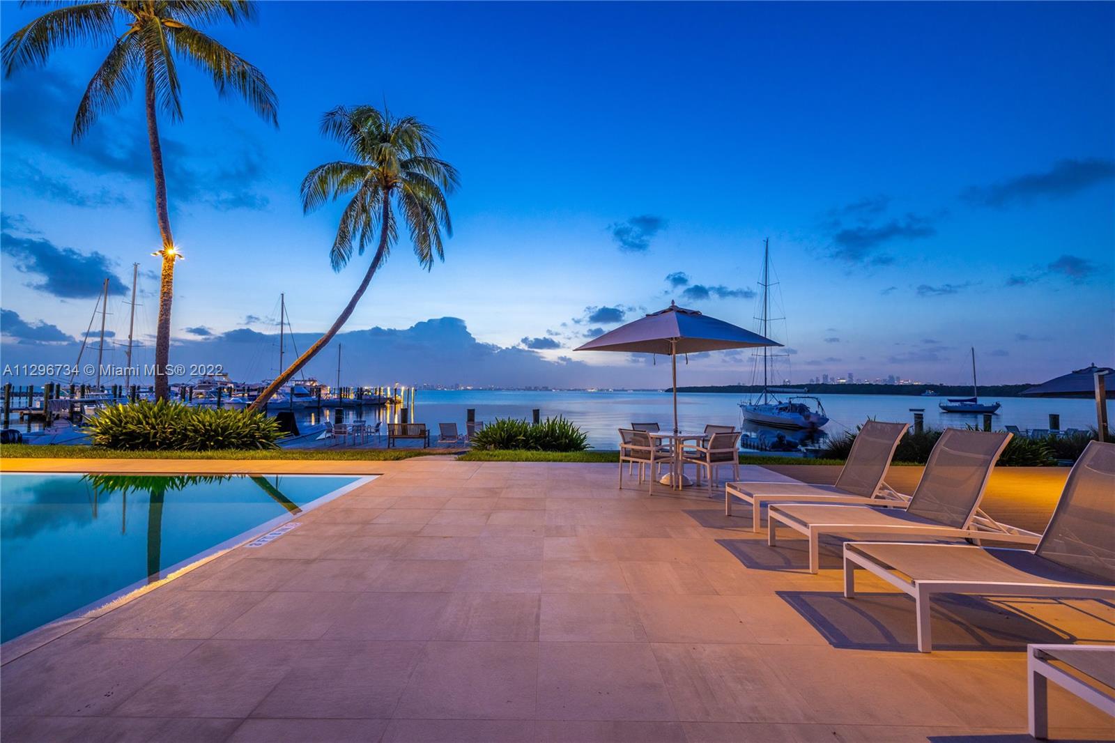 166 Harbor Drive, Unit 1A Key Biscayne, FL 33149 - Photo 47 of 86 a view of a swimming pool with a table and chairs under an umbrella