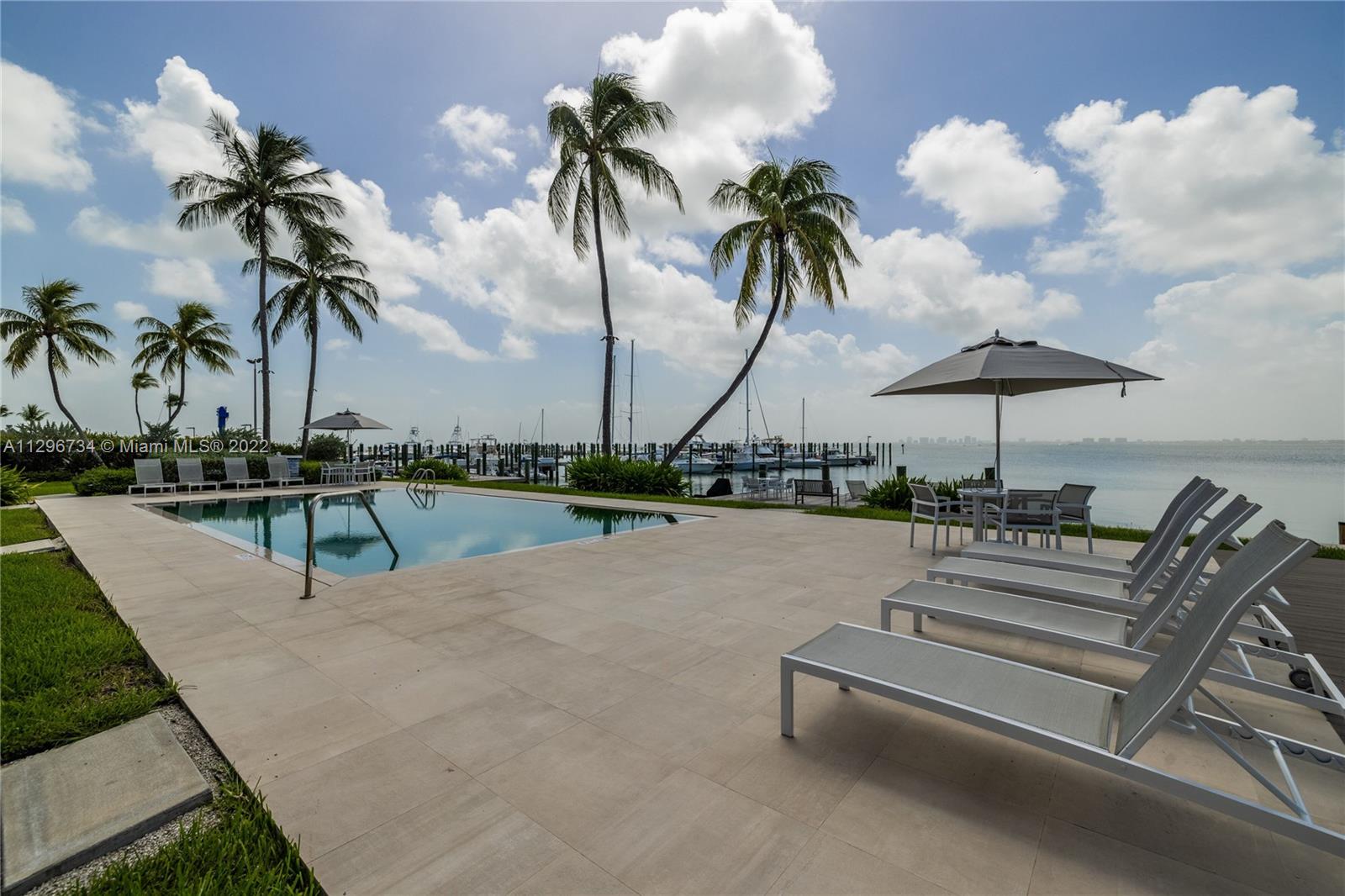 166 Harbor Drive, Unit 1A Key Biscayne, FL 33149 - Photo 59 of 86 a view of a swimming pool with a table and chairs