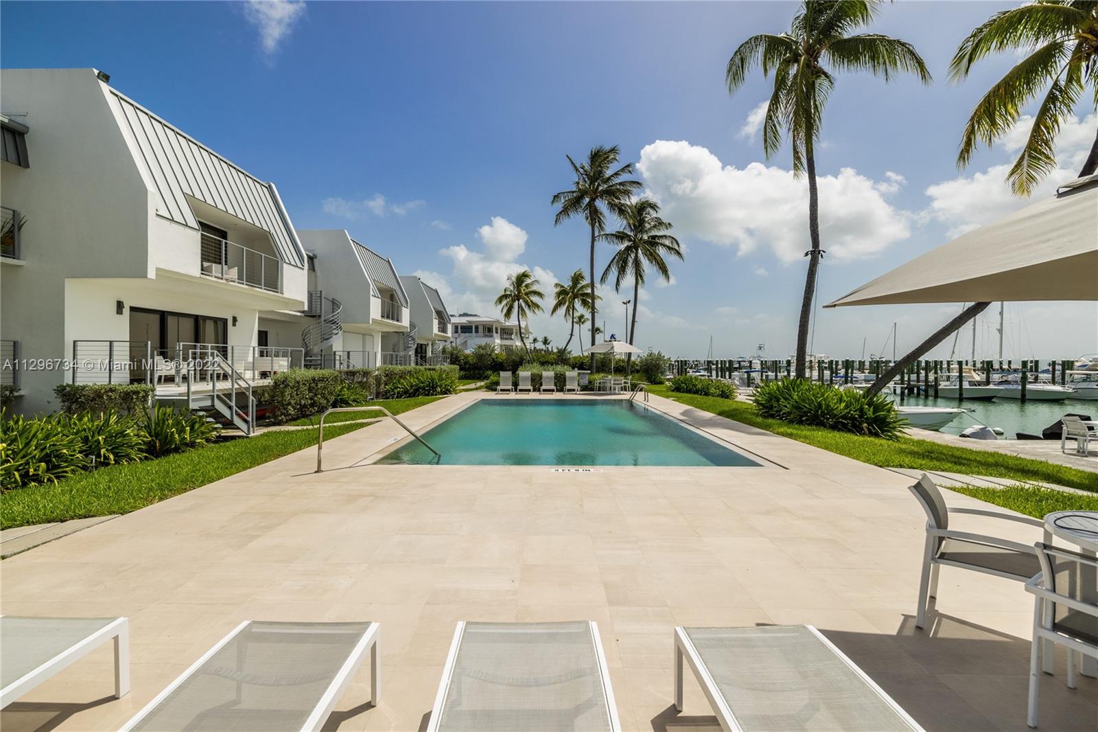 166 Harbor Drive, Unit 1A Key Biscayne, FL 33149 - Photo 72 of 86 a view of a swimming pool with a lawn chairs and palm trees