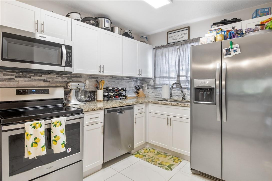 727 Banks Road, Unit 98 Margate, FL 33063 - Photo 11 of 22 a kitchen with stainless steel appliances granite countertop a refrigerator stove and microwave