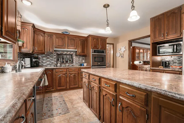 a kitchen with stainless steel appliances granite countertop a sink a stove and a wooden cabinets