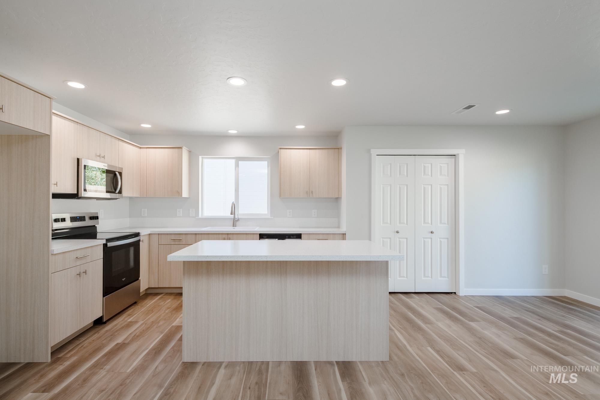 13699 Judson Street Caldwell, ID 83607 - Photo 3 of 26 Kitchen featuring light brown cabinetry, appliances with stainless steel finishes, light countertops, modern cabinets, and light wood-type flooring
