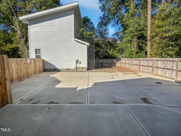 a view of backyard with large tree and wooden fence