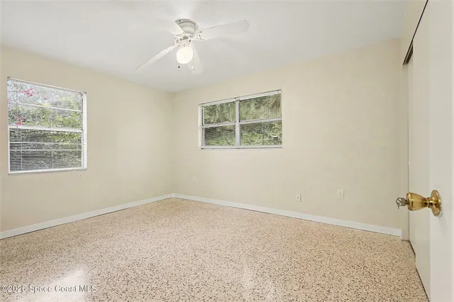 an empty room with windows and fan
