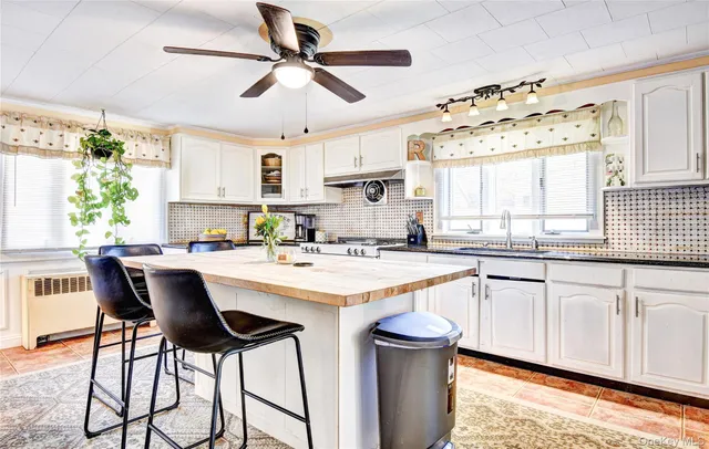 a kitchen with stainless steel appliances granite countertop white cabinets a sink and a large window