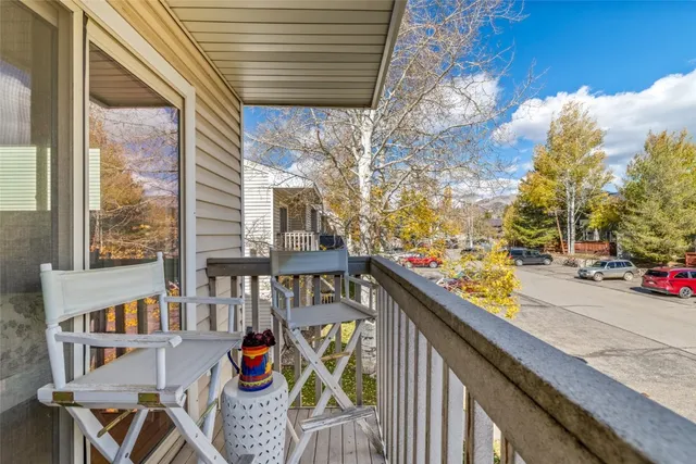 a balcony view with couple of cars parked on road in front of house