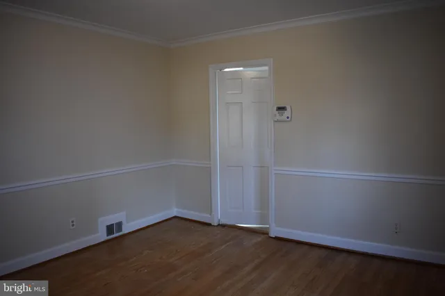 an empty room with wooden floor and white walls