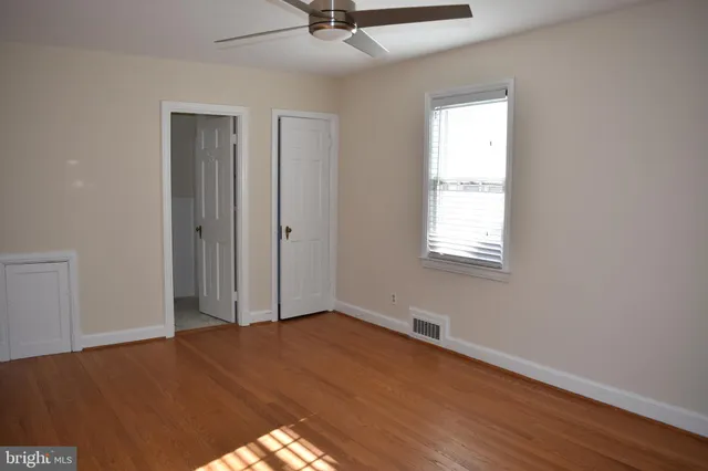 a view of an empty room with a window and wooden floor