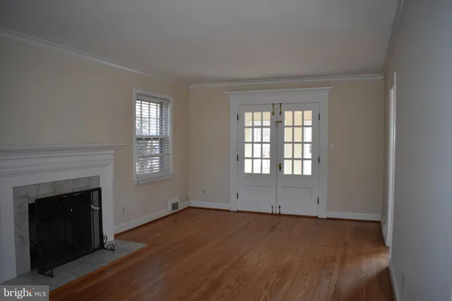an empty room with wooden floor fireplace and windows
