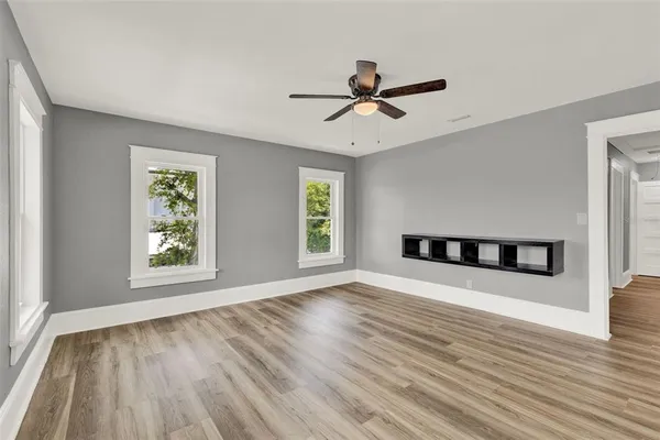 a view of an empty room with wooden floor and a window