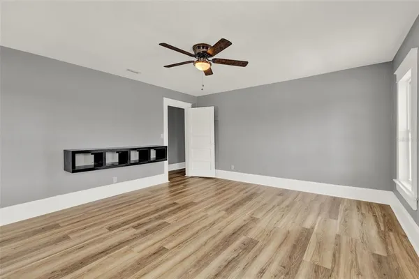 a view of empty room with wooden floor and fan