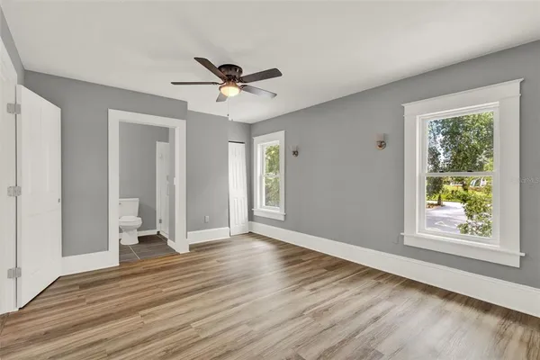 a view of an empty room with a window and wooden floor