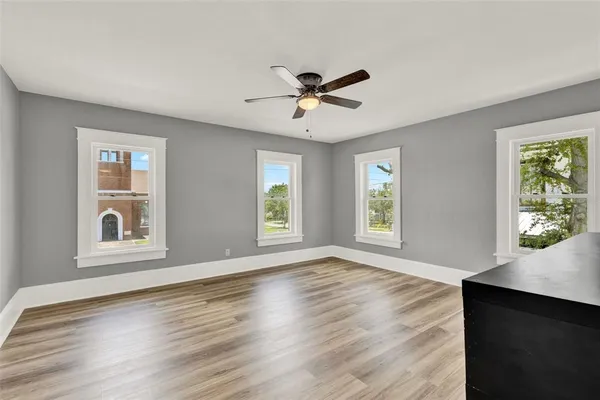a view of an empty room with a window and wooden floor