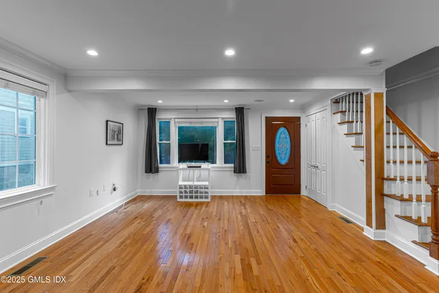a view of an empty room with wooden floor and a window