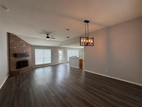 a view of a room with wooden floor fireplace and window
