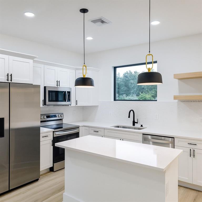 2967 Barry Road North Port, FL 34286 - Photo 5 of 16 a kitchen with stainless steel appliances a sink a stove a refrigerator and a window