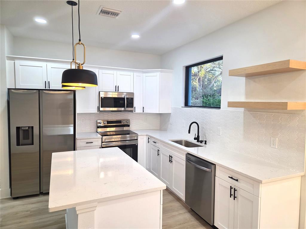 2967 Barry Road North Port, FL 34286 - Photo 6 of 16 a kitchen with stainless steel appliances granite countertop a sink a stove a refrigerator a center island with wooden floor and cabinets