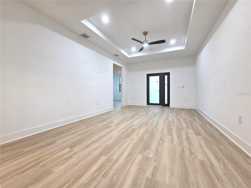 2967 Barry Road North Port, FL 34286 - Photo 7 of 16 an empty room with wooden floor ceiling fan and windows