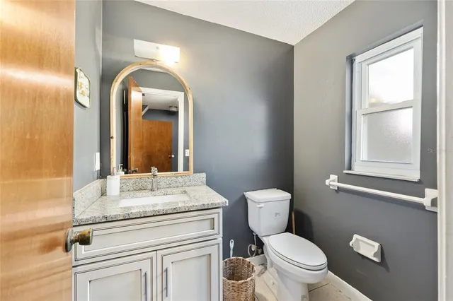 a bathroom with a granite countertop toilet a sink and mirror