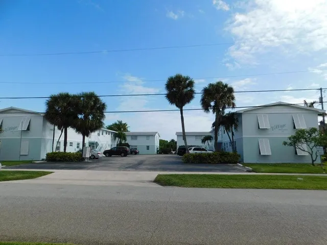 a front view of a house with a yard and palm trees