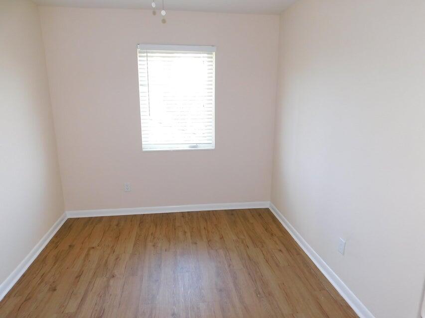741 Hummingbird Way, Unit 8 North Palm Beach, FL 33408 - Photo 9 of 13 an empty room with wooden floor and windows