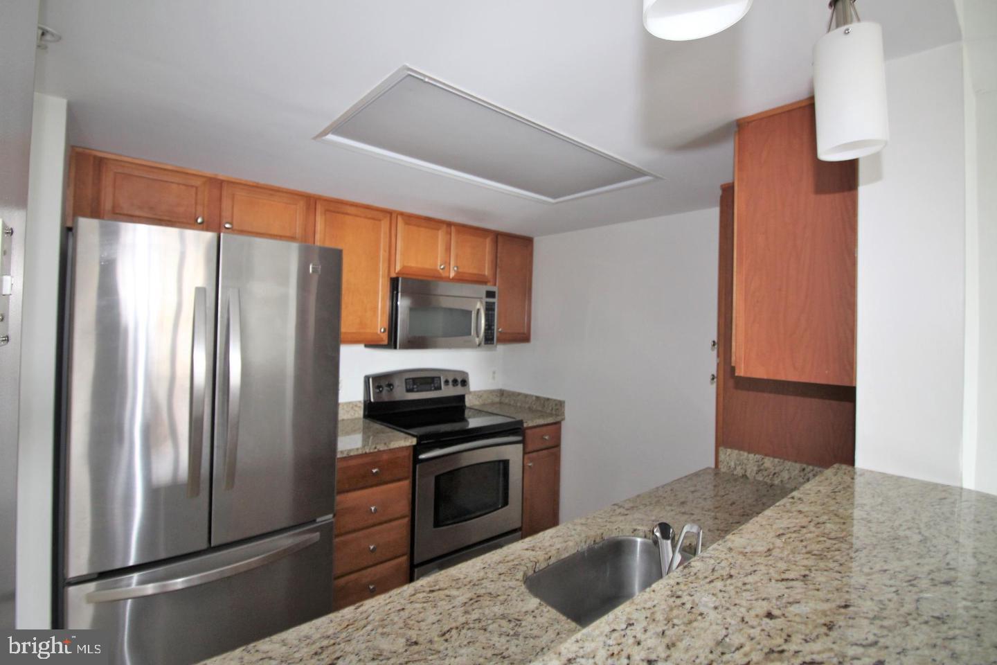 11800 Sunset Hills Road, Unit 625 Reston, VA 20190 - Photo 7 of 19 a kitchen with stainless steel appliances granite countertop a refrigerator a stove and a sink with wooden floor