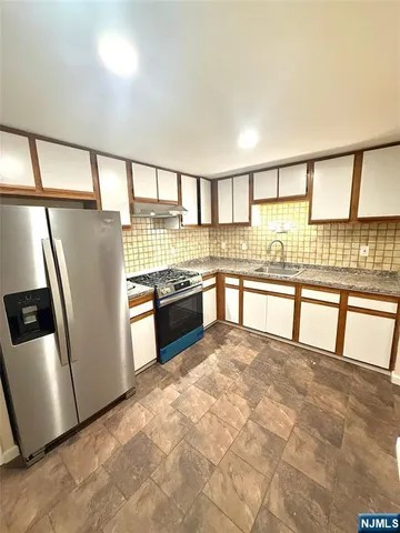 a view of a kitchen with stainless steel appliances granite countertop a stove a sink and a refrigerator