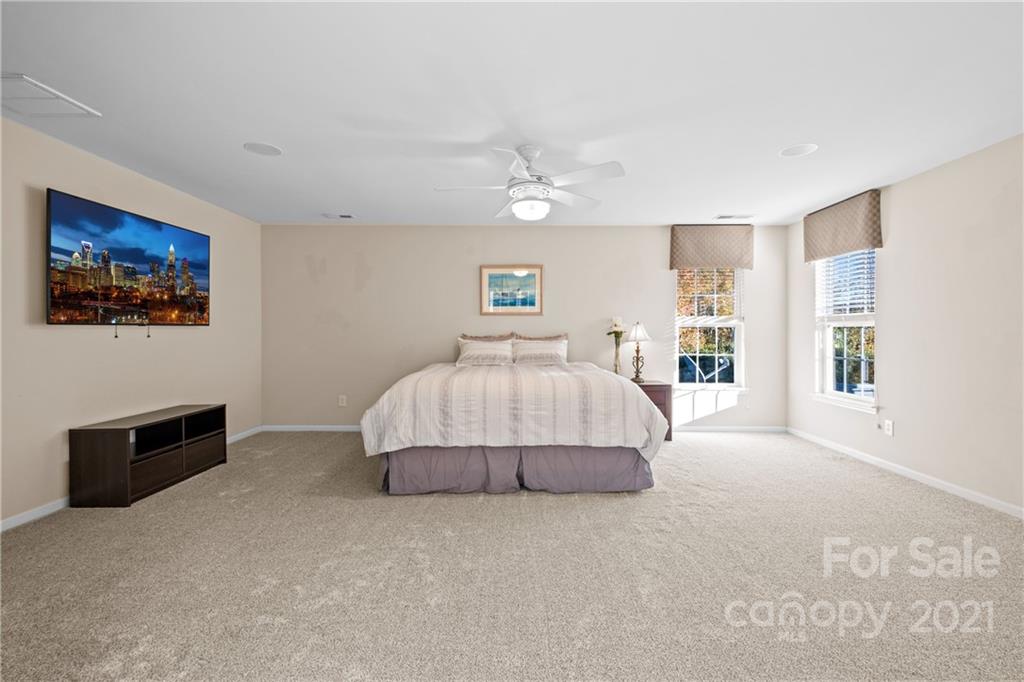 14448 Laurel Tree Lane Huntersville, NC 28078 - Photo 22 of 34 a spacious bedroom with a bed and a chandelier