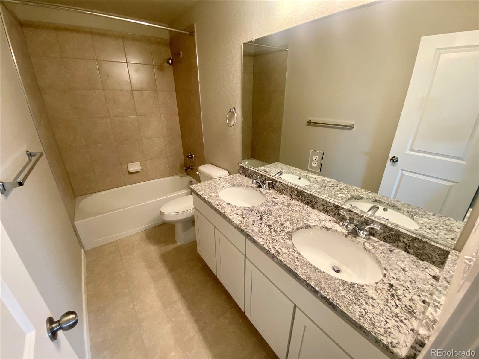 541 Ryan Avenue Fort Lupton, CO 80621 - Photo 27 of 29 a bathroom with a granite countertop sink a mirror and a bathtub