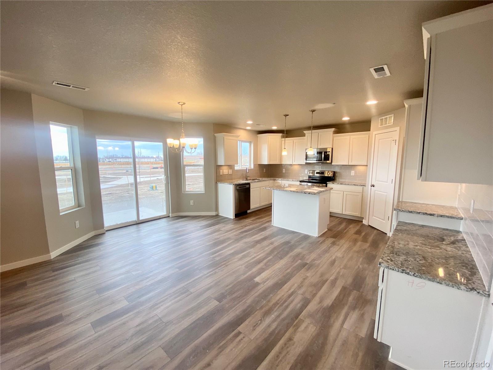 541 Ryan Avenue Fort Lupton, CO 80621 - Photo 3 of 29 a kitchen with stainless steel appliances granite countertop a refrigerator a sink dishwasher a stove and white countertops with wooden floor