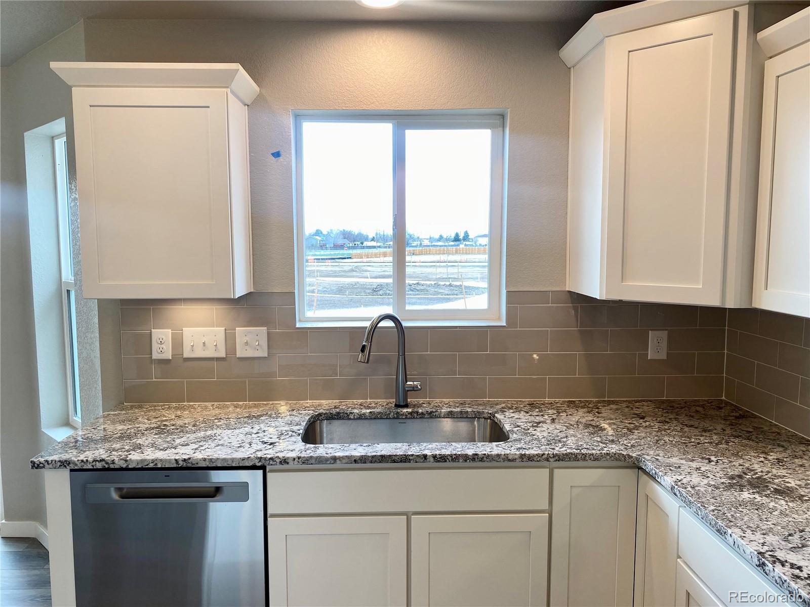 541 Ryan Avenue Fort Lupton, CO 80621 - Photo 5 of 29 a kitchen with granite countertop a sink a window and cabinets