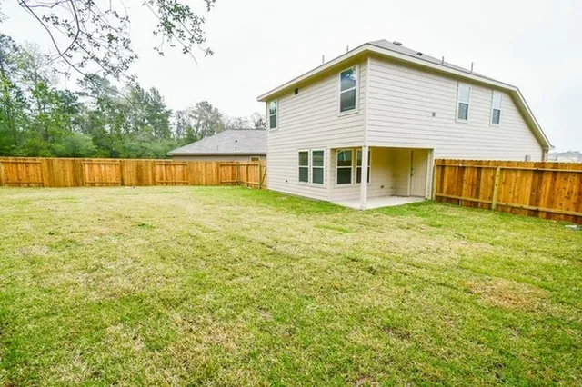 a view of a house with a yard and a large tree