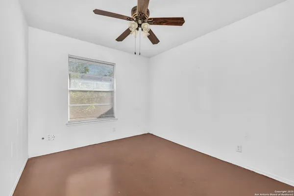 an empty room with a window and a fan