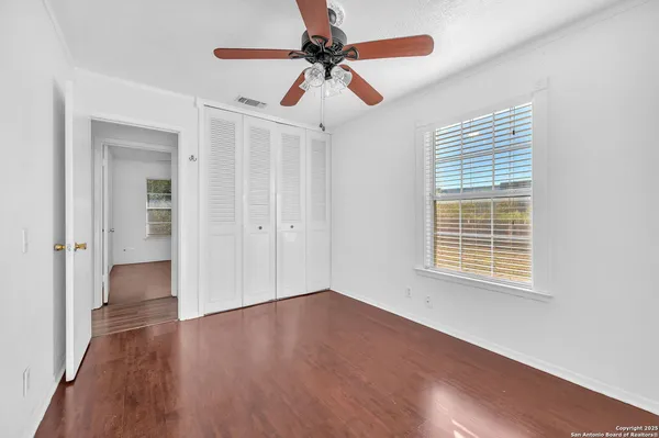 a view of an empty room with window and wooden floor