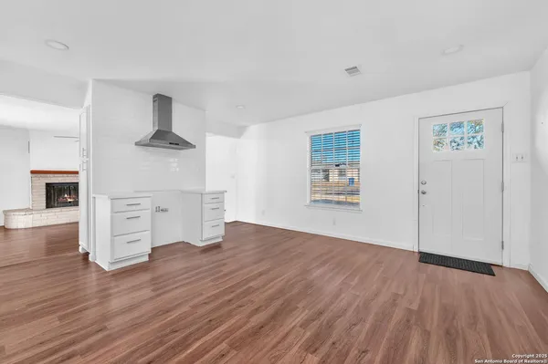 an empty room with wooden floor cabinet and windows