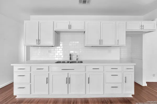 a kitchen with white cabinets and sink