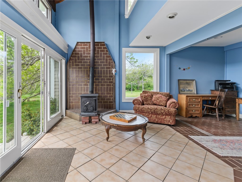 1303 Old Mill Road Block Island, RI 02807 - Photo 19 of 50 From kitchen are sliders out to the backyard, a perfect place to grill and entertain. This room has a wood burning stove, vaulted ceiling, large picture window, and office area. Would make a great den area next to the kitchen.