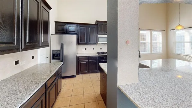 a kitchen with granite countertop a sink a stove and refrigerator