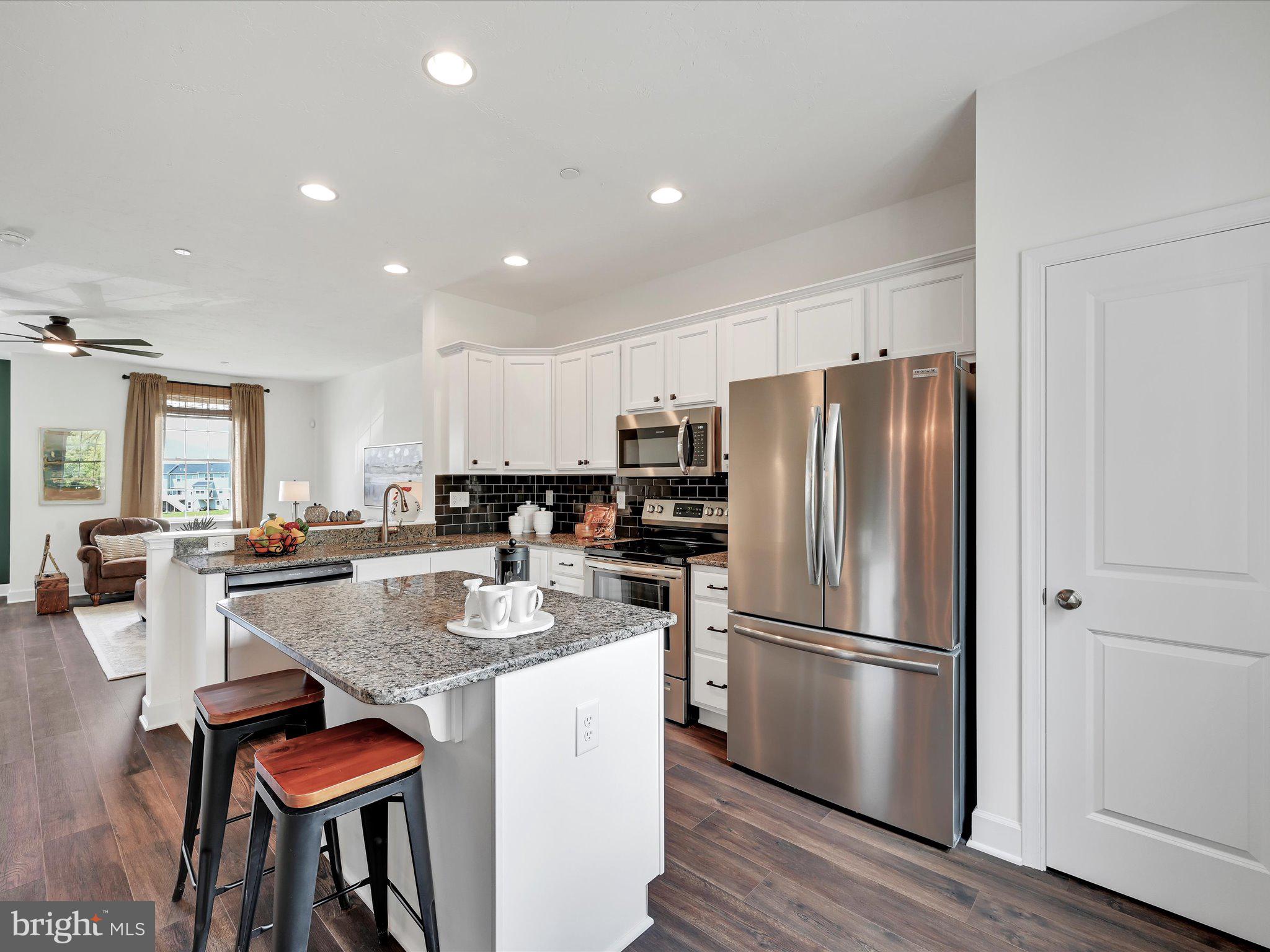 123 Holstein Drive, Unit 161 Hanover, PA 17331 - Photo 2 of 18 a kitchen with stainless steel appliances granite countertop a refrigerator a stove a sink a dining table and chairs with wooden floor