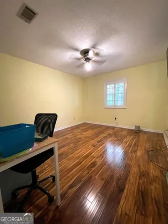 a view of a room with wooden floor and ceiling fan