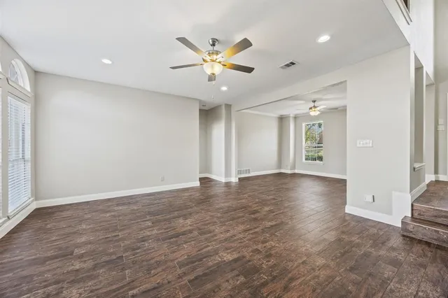 a view of an empty room with window and wooden floor