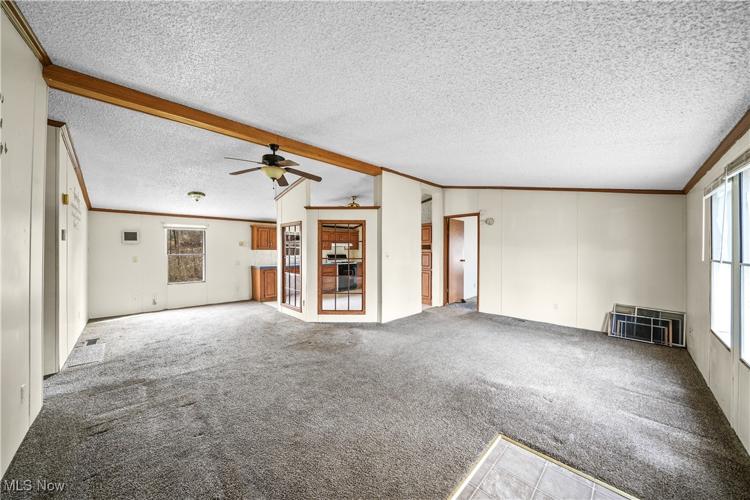 3792 Selnik Road Kent, OH 44240 - Photo 2 of 39 Unfurnished living room with lofted ceiling with beams, carpet, heating unit, and crown molding