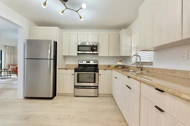 a kitchen with granite countertop white cabinets and stainless steel appliances