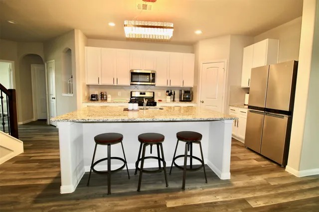 a large kitchen with a table chairs refrigerator and microwave