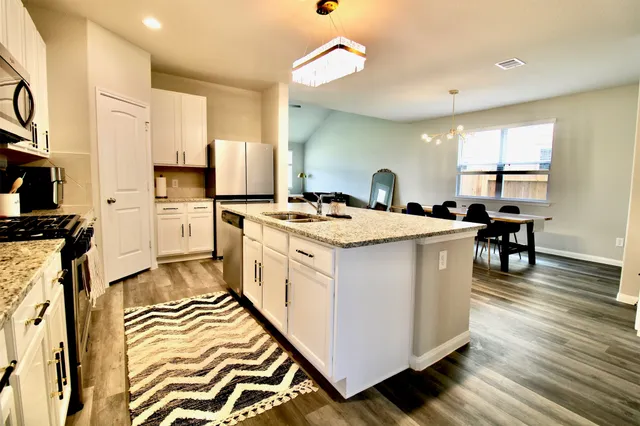a kitchen with a stove a sink dishwasher and a refrigerator with wooden floor