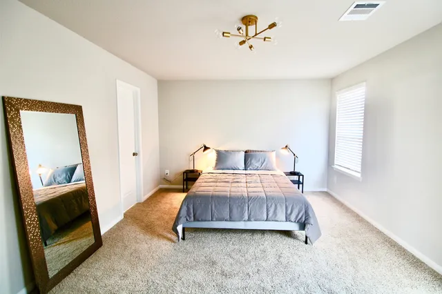 a bedroom with a bed and a mirror on the dresser