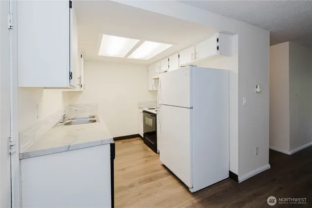 a kitchen with a refrigerator a sink and wooden floor