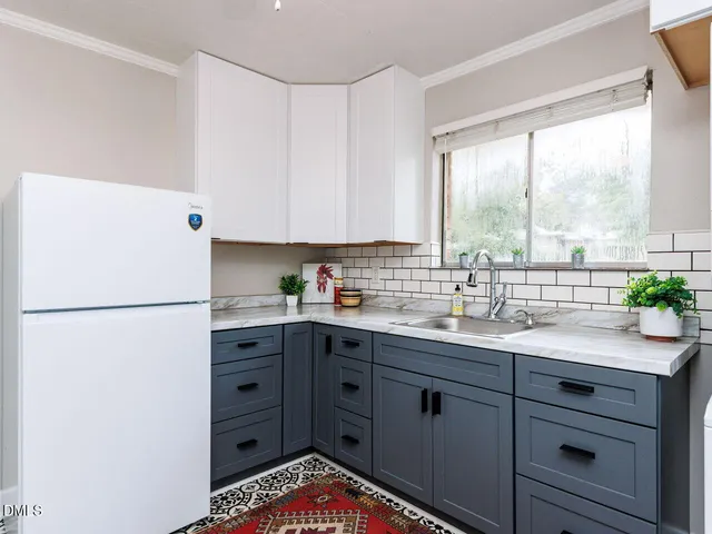 a kitchen with a sink a refrigerator and a large window
